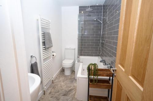 a bathroom with a tub and a toilet and a sink at 4 Bedroom Winchester Town House, central, parking in Winchester