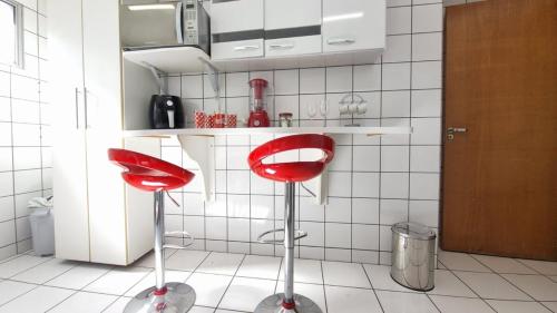 a kitchen with two red stools in a kitchen at 3 bedrooms with heated pool Temporada Brasilia in Brasilia