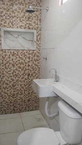 a bathroom with a white toilet and a sink at Casa do 40 horas in Ananindeua