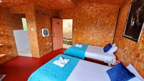 a room with two beds and a door to another room at Refugio Ecolodge Shapingo in Moyobamba