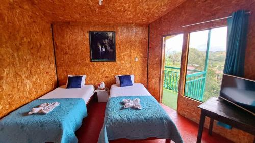 two beds in a room with a tv and a window at Refugio Ecolodge Shapingo in Moyobamba