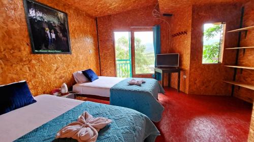 a room with two beds and a tv and windows at Refugio Ecolodge Shapingo in Moyobamba