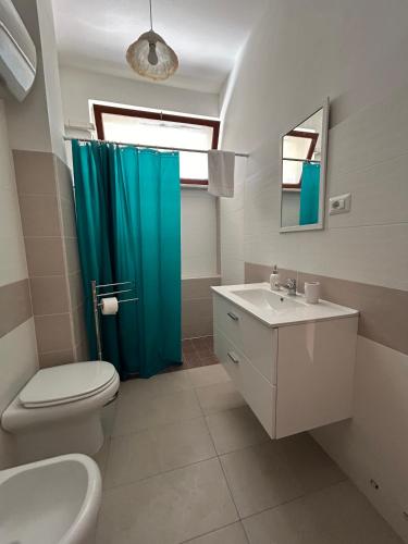 a bathroom with a toilet and a blue shower curtain at casa al mare per famiglie 2 in Minturno