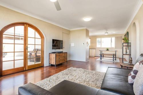 a living room with a couch and a tv at Tranquil Arches Indooroopilly in Brisbane