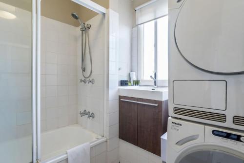 a bathroom with a shower and a sink and a washing machine at Tranquil Arches Indooroopilly in Brisbane