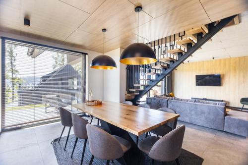 a dining room with a wooden table and chairs at Trzy Szyszki Maniowy Domki Jezioro Czorsztyńskie Balia oraz Sauna w cenie in Maniowy