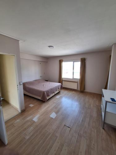 a bedroom with a bed and a wooden floor at Departamento Emanuel in Comodoro Rivadavia