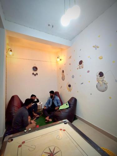a group of three men sitting in a living room at Nomad's Nest Backpackers Hostel in Guwahati