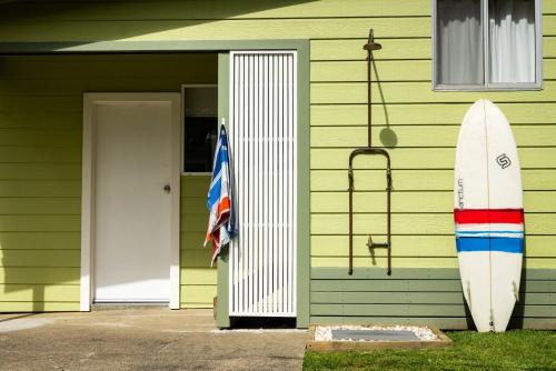 a surfboard leaned up against a house with a flag at Golden Sands Pet Friendly 2 Mins Walk to Beach in Culburra Beach