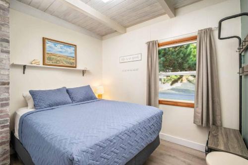Un dormitorio con una cama azul y una ventana. en The Little Sand Castle, en Rockaway Beach
