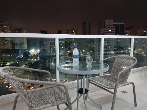 a table with two chairs and a bottle of water on a balcony at Excelente e moderno apartamento com linda vista in Vitória