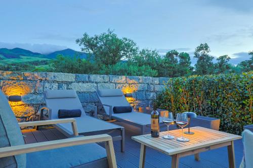 a patio with two chairs and a table with wine glasses at Assomada House in Nordeste