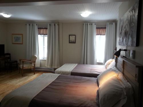 a bedroom with two beds and two windows at Auberge la maison sous les pins in Saint-Joseph-de-la-Rive