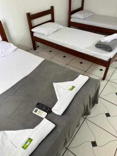 two beds with white towels and a remote control at Kitnet Praia Grande in Arraial do Cabo