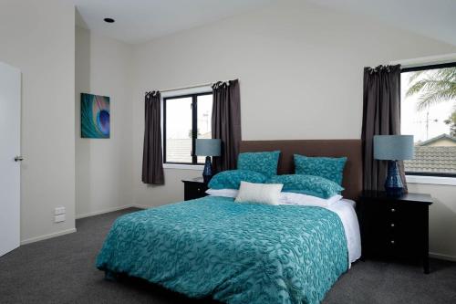a bedroom with a bed with a blue comforter at Mt Maunganui White House in Mount Maunganui