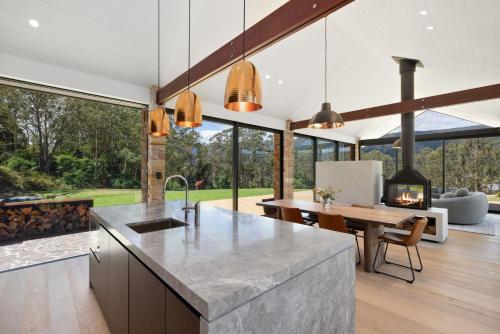 BarrengarryにあるVilla Arbosana, Barrengarry, Kangaroo Valleyのテーブルと暖炉のあるオープンキッチン