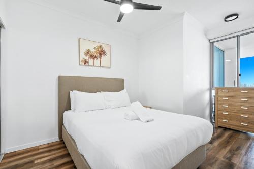 a white bedroom with a large bed and a window at Harbour Quays Apartments in Gold Coast