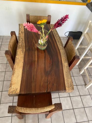 a wooden table with a vase of flowers on it at DEPA IXTLAN alberca y cerca de playa in Santa Cruz Huatulco