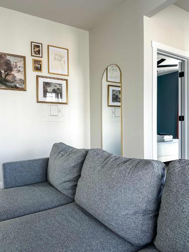 a gray couch in a living room with a mirror at StayAE Downtown - One Bedroom, 2nd Floor in Baton Rouge