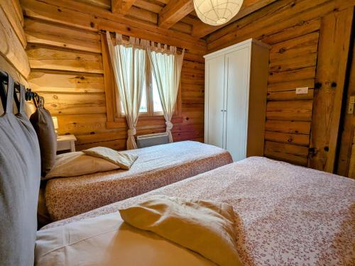 a bedroom with two beds in a log cabin at Chalet tout confort en bois, Wifi, Animaux admis - FR-1-589-756 in Anould