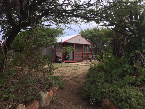 a house with a red roof in a garden at Klein Paradys Lodge - Polokwane in Polokwane