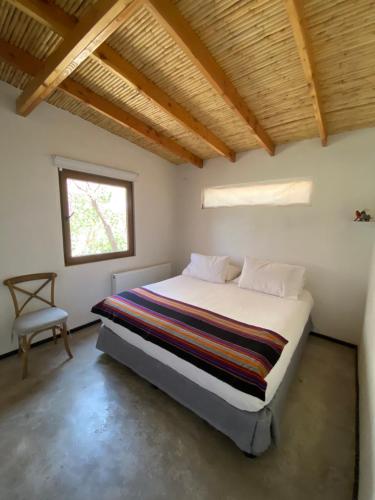 a bedroom with a bed and a window and a chair at Casa Luna in San Pedro de Atacama