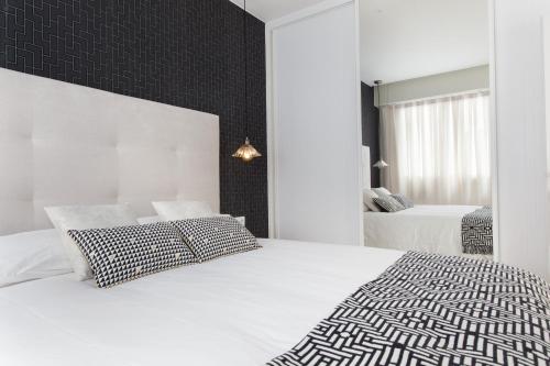 Passeig de Gracia Apartment في برشلونة: غرفة نوم بيضاء بسريرين ومرآة