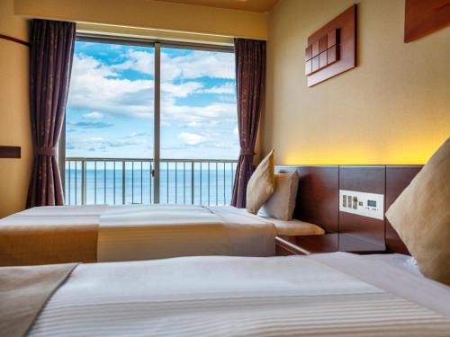 a hotel room with two beds and a large window at KAMENOI HOTEL Atami in Atami
