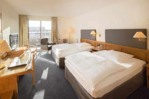 um quarto de hotel com duas camas e uma secretária em Hotel Heidehof garni em Büdelsdorf