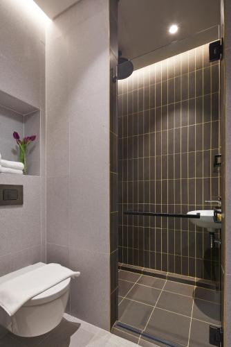 a bathroom with a toilet and a glass shower at Citadines Connect City Centre Singapore in Singapore