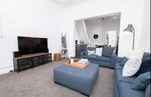 a living room with blue couches and a flat screen tv at The Paddington Bathurst #8 in Bathurst