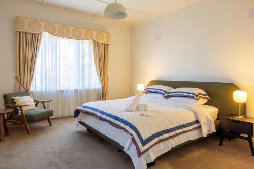 a bedroom with a bed and a chair and a window at Prime Location House with Pool in Kew in Melbourne