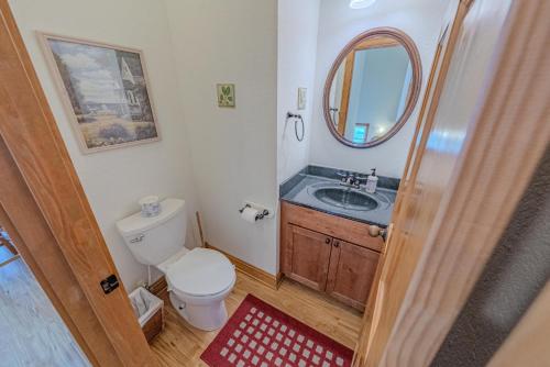 a bathroom with a toilet and a sink and a mirror at Frolic Inn OBX - Semi Soundfront Retreat, Pool, Hot Tub, Boat Ramp, Elevator, Media & Game Room in Rodanthe