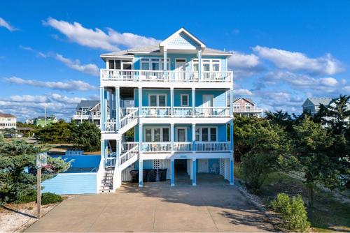 a blue and white house with a balcony at Frolic Inn OBX - Semi Soundfront Retreat, Pool, Hot Tub, Boat Ramp, Elevator, Media & Game Room in Rodanthe