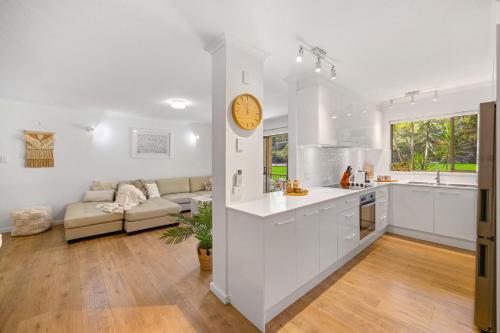 a kitchen and living room with a couch and a clock at Shelly Cove Apt 12 - common pool in Port Macquarie
