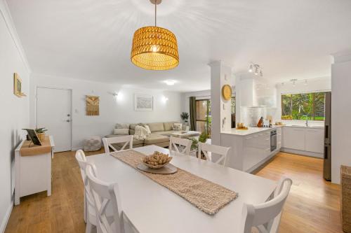 a kitchen and living room with a white table and chairs at Shelly Cove Apt 12 - common pool in Port Macquarie