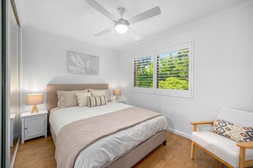 a bedroom with a bed and a window and a chair at Shelly Cove Apt 12 - common pool in Port Macquarie