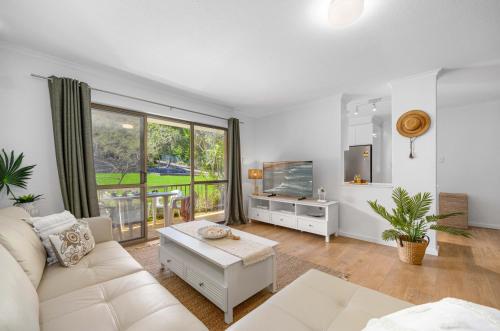 a living room with a white couch and a tv at Shelly Cove Apt 12 - common pool in Port Macquarie