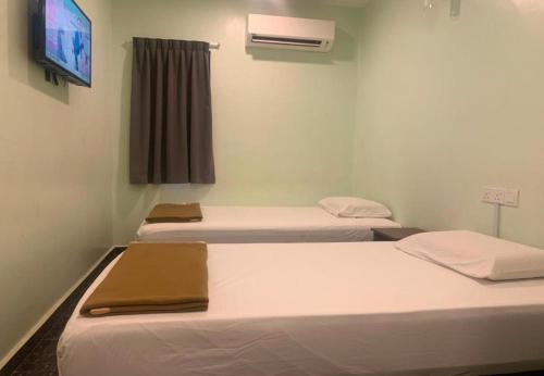 a room with three beds and a tv on the wall at TH Hotel in Bahau