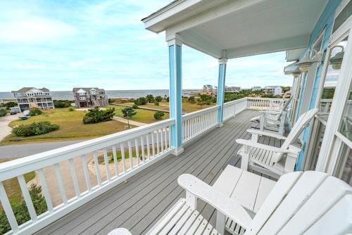 a porch with white chairs and a view of the ocean at Frolic Inn OBX - Semi Soundfront Retreat, Pool, Hot Tub, Boat Ramp, Elevator, Media & Game Room in Rodanthe