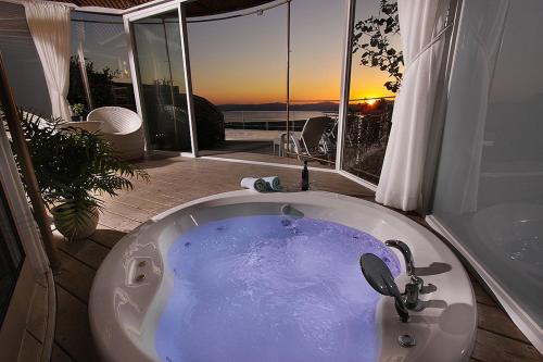 a bath tub in a bathroom with a view of the sunset at Sea Zen Resort in Ma'ale Gamla
