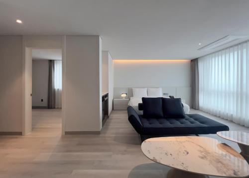 a living room with a black couch and a bed at Ocean Suites Jeju Hotel in Jeju