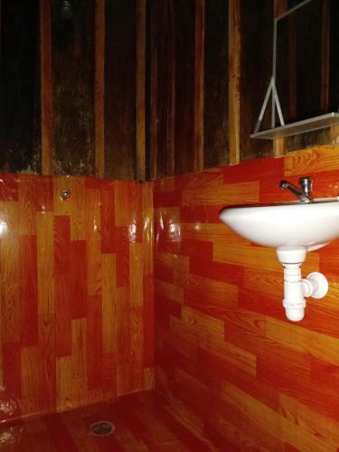a bathroom with a white sink on a wooden wall at Antares Jungle Lodge in Miraflores