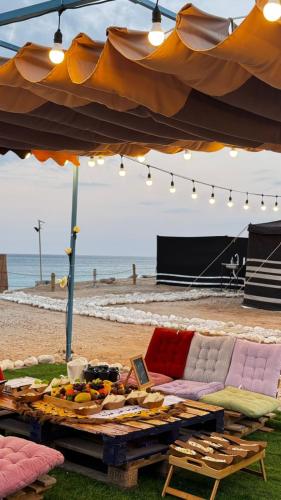 a picnic table on the beach under an umbrella at ROYAl FINS CAMP in Fins