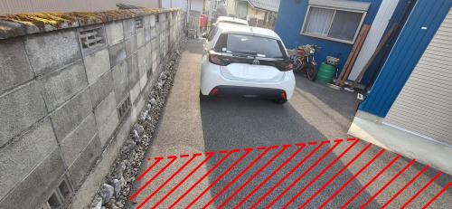 a small white car parked next to a wall at 茂平の宿 in Yoro