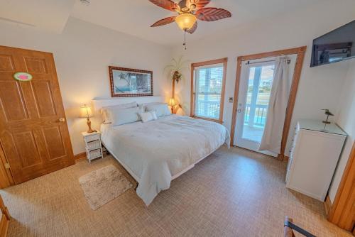 a bedroom with a bed and a ceiling fan at Frolic Inn OBX - Semi Soundfront Retreat, Pool, Hot Tub, Boat Ramp, Elevator, Media & Game Room in Rodanthe