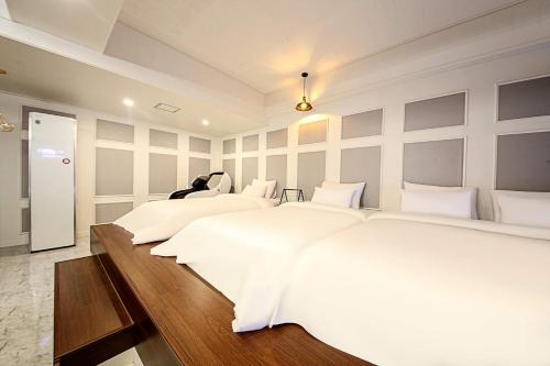 two beds in a bedroom with white walls at Fine Avenue Hotel in Changwon