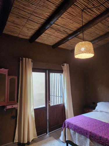 a bedroom with a bed with purple sheets and a window at La Gauda in Huacalera