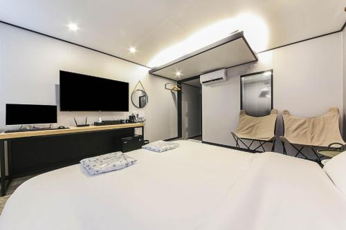 a bedroom with a bed and a desk with a television at Fine Avenue Hotel in Changwon