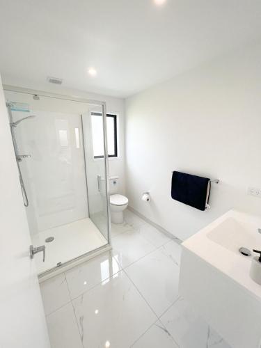 a white bathroom with a shower and a toilet at Coastal Charm Escape in Karikari Peninsula